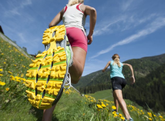 gros plan sur le bas d'une chaussure de course, deux femmes courant à travers le champ, concept des pires chaussures de course qui vous font mal aux pieds