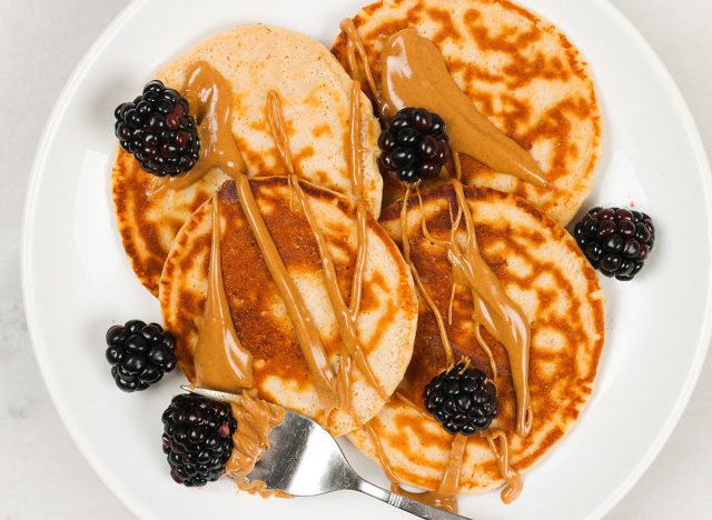 crêpes protéinées au beurre de cacahuète et aux mûres sur une assiette blanche