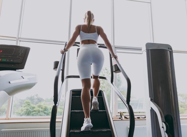 femme de remise en forme faisant de l'entraînement StairMaster à la salle de sport, vue arrière