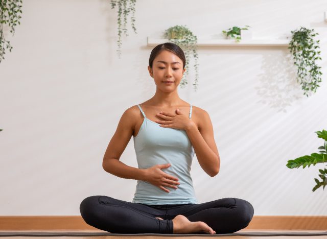 femme faisant des exercices de respiration profonde sur un tapis de yoga