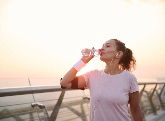 femme buvant de l'eau en bouteille pendant une promenade à l'extérieur, concept de la façon de perdre 10 livres sans régime