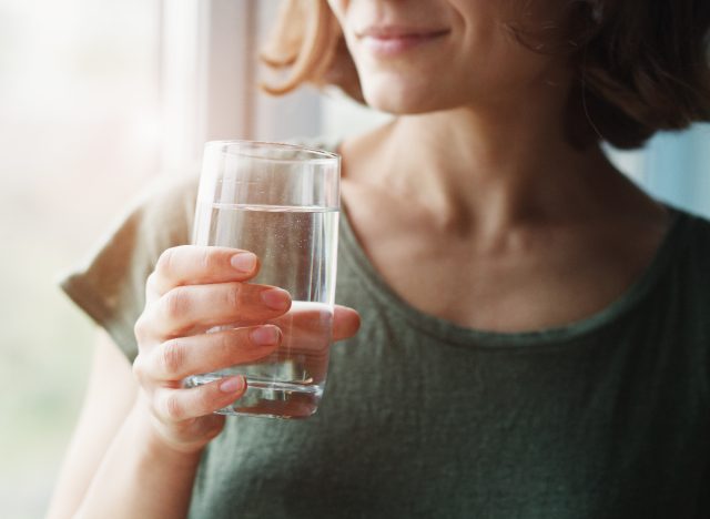 femme en gros plan tenant un verre d'eau, concept de conseils de perte de graisse du ventre pour les femmes